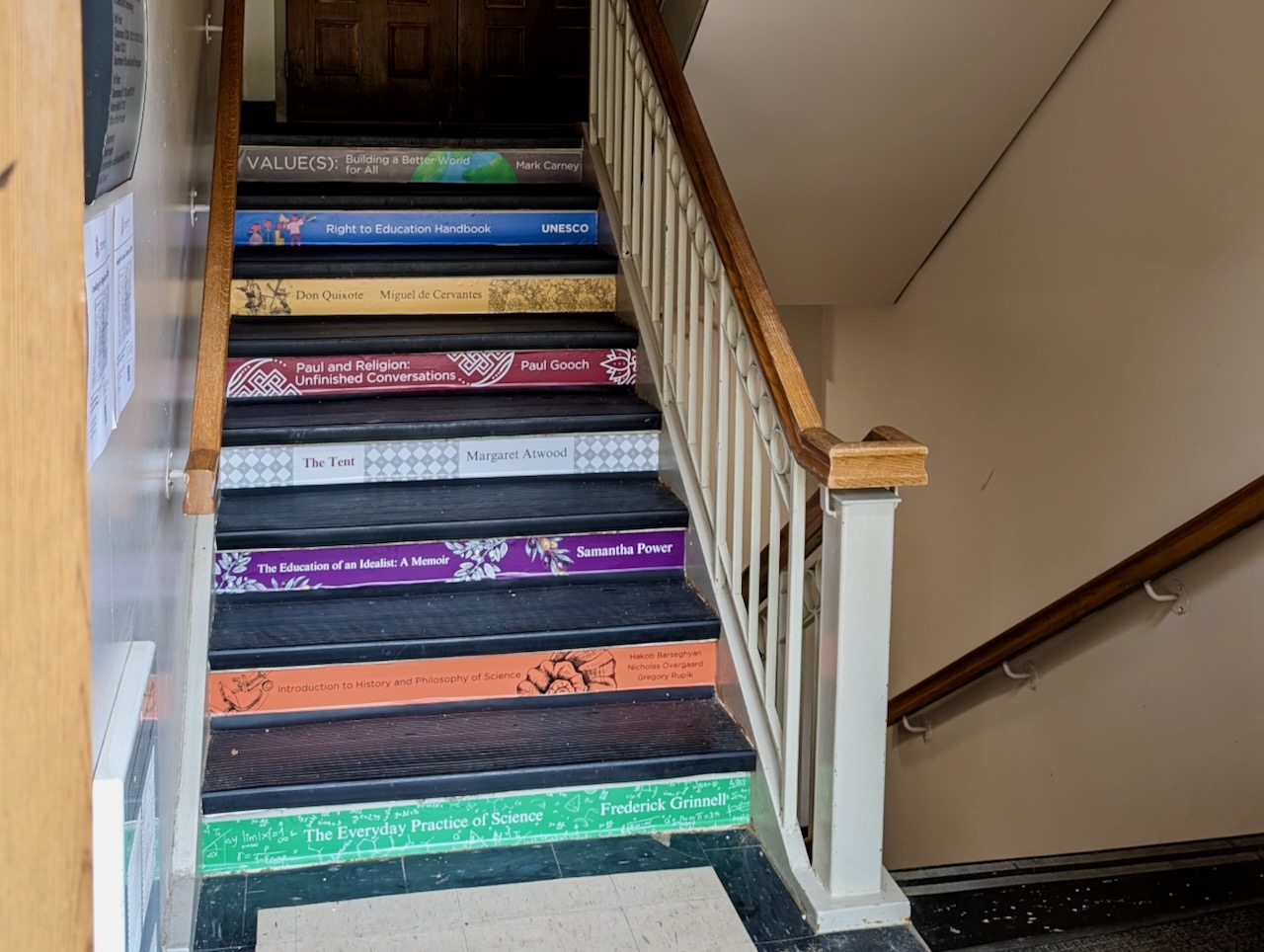 Stairs lined with decals resembling book covers in the Old Vic building.