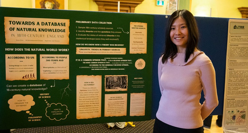 Grace Shan stands in Old Vic in front of a poster displaying her research. 