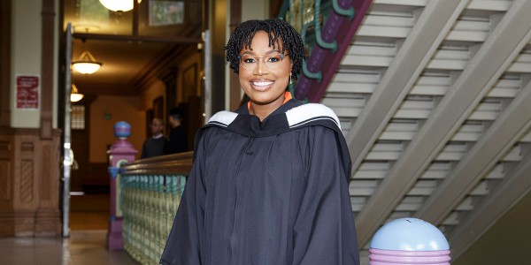 Imani King standing in the stairwell of Old Vic building in her graduation gown.