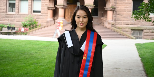Vic graduate Khulan Enkhbold in her graduation gown in front of Old Vic building.
