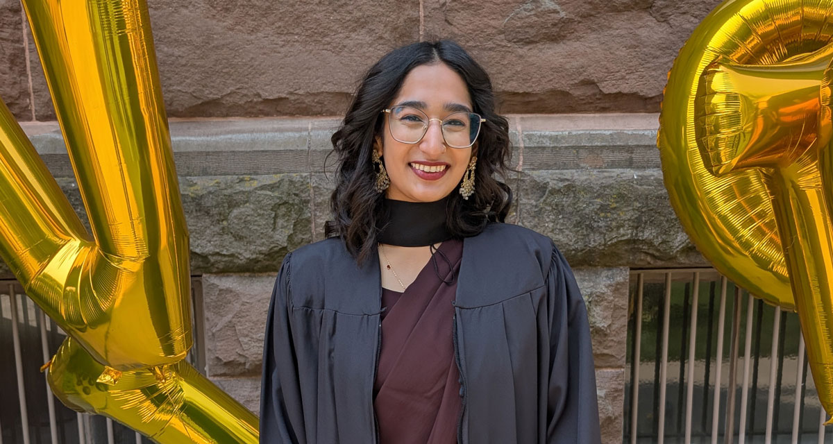 Laila Vahed poses in front of the Old Vic building on convocation day in a black graduation gown.