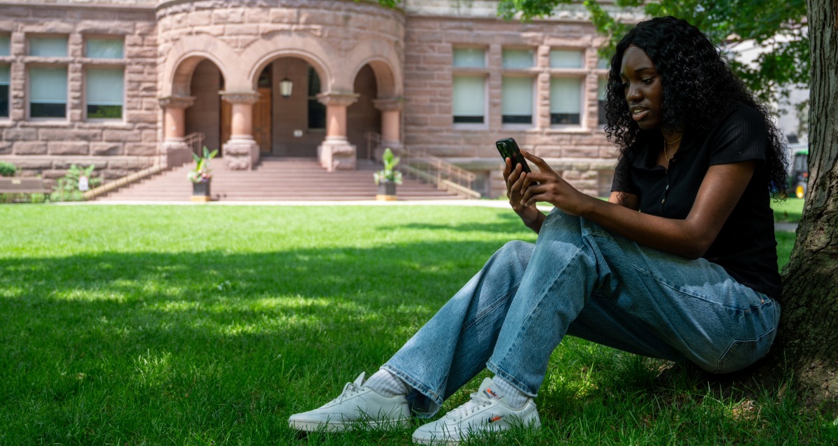Favour Ebamhanhon seated on the Vic quad looking at her phone.