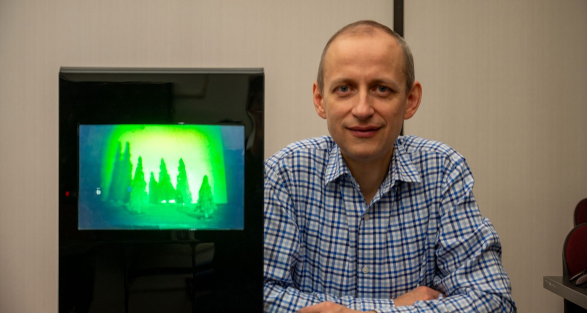 Emanuel Istrate sits alongside a hologram created in his course.