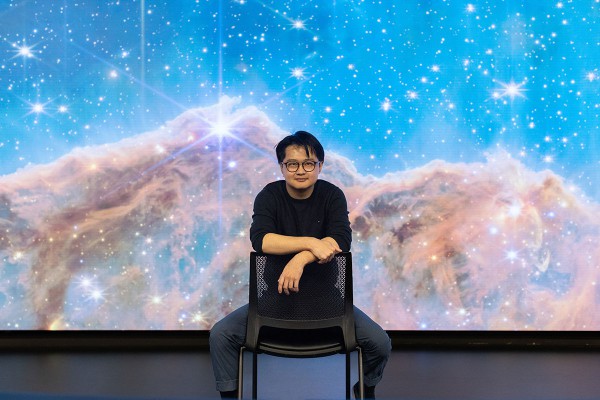Peter Ma sitting in a chair in front of a screen featuring stars and space.