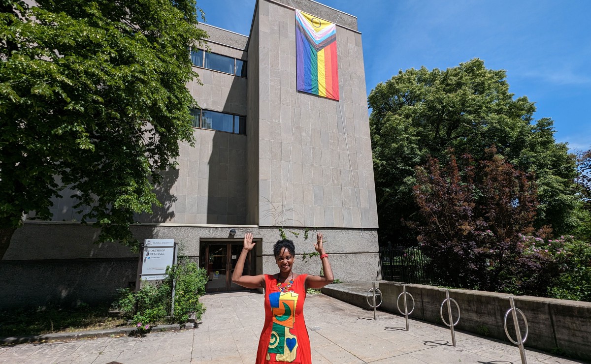 Rhonda McEwen pointing to a Progress Pride flag.